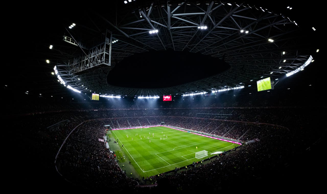 Aerial view of a night football match in Budapest. Illuminated stadium full of fans adds dramatic atmosphere.